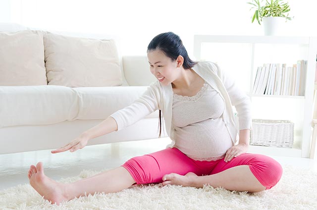 Pregnant woman stretching in her living room