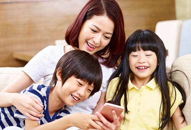 Mother with son and daughter playing with smartphone
